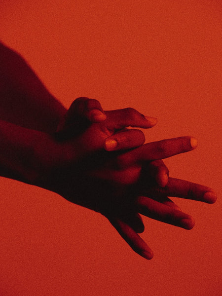 hands clasping together against red background