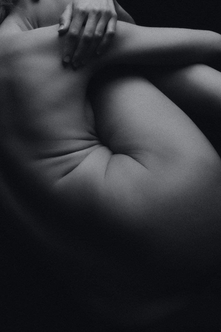 black and white image of a naked woman hugging herself