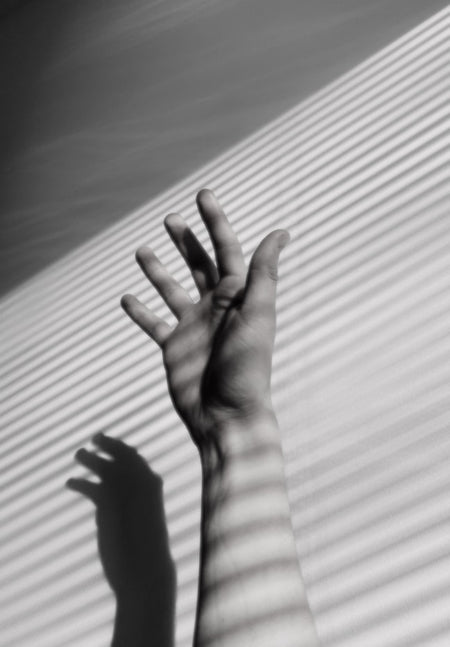 black and white hand with rays of sun against wall